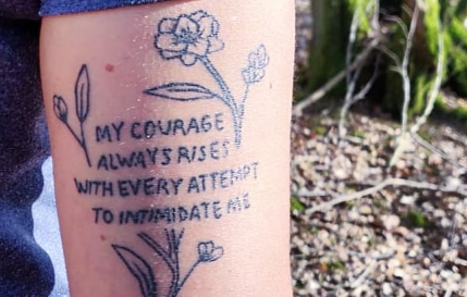 A tattoo over a forearm that says My courage always rises with every attempt to intimidate me