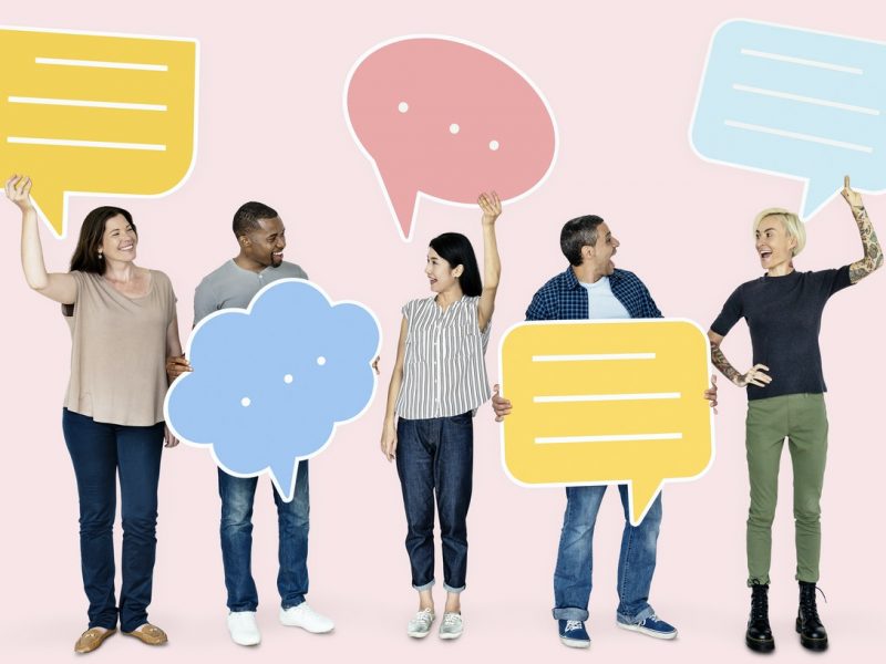 5 people standing up holding conversation bubbles