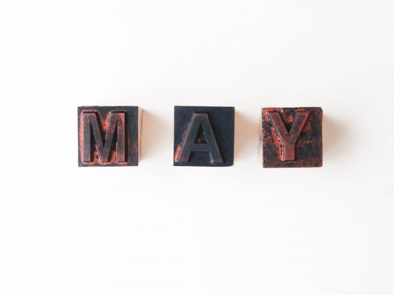 the letters M, A and Y over wooden stamps, forming the word MAY