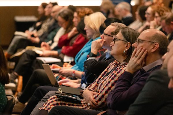 A photo of a row of people sat looking up and listening