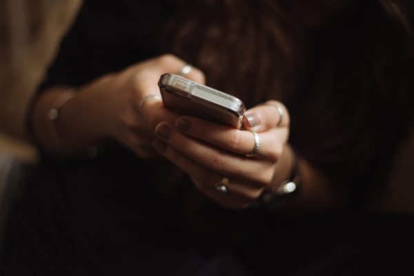 A close up of a woman's hands wearing silver rings pressing buttons on a mobile phone.